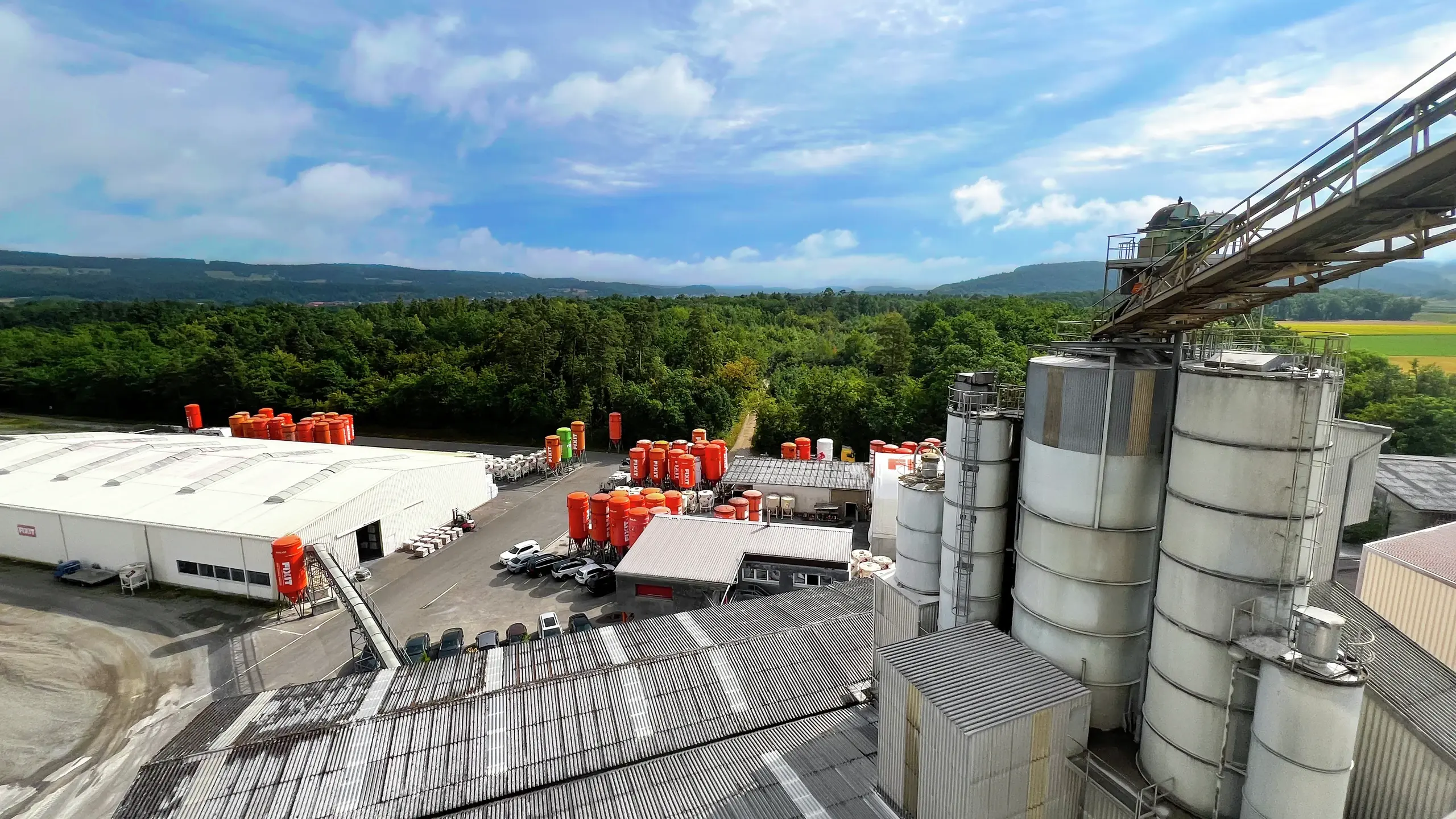 Usine de production équipée d'un convoyeur à pierres, de silos Fixit orange et de hangars