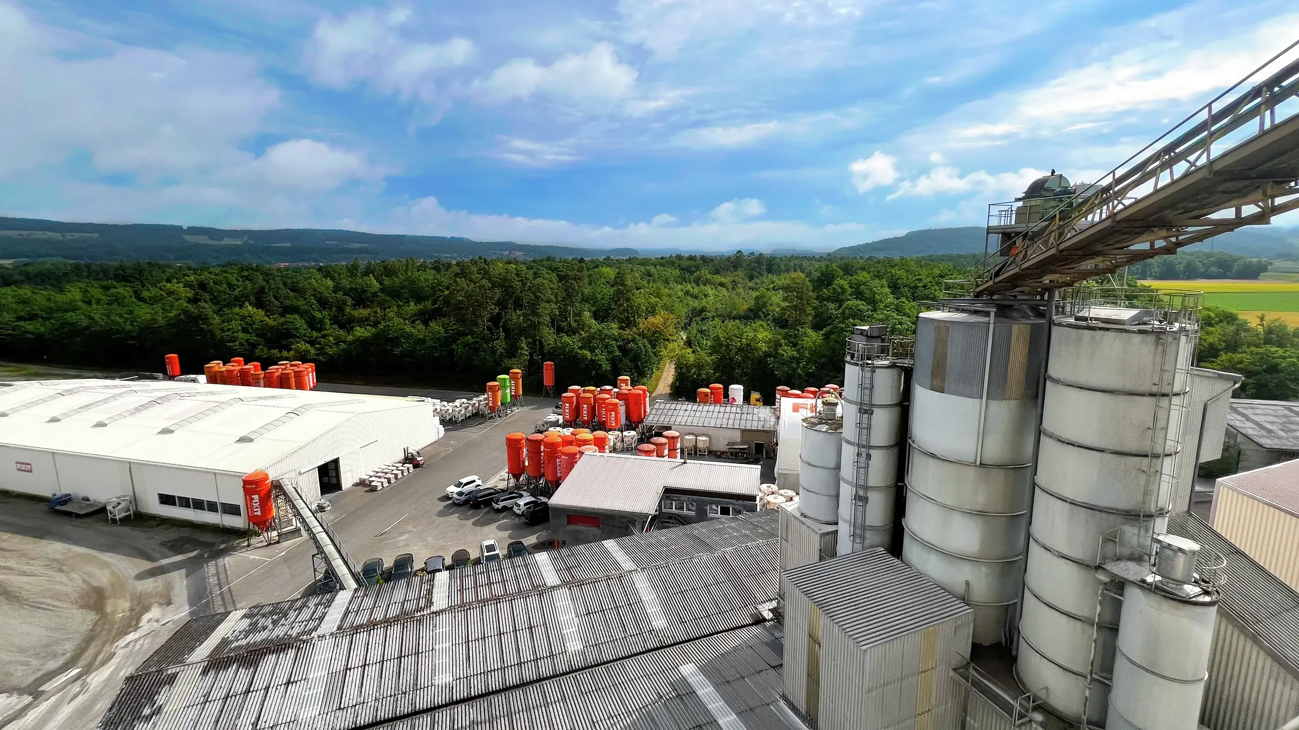 Usine de production équipée d'un convoyeur à pierres, de silos Fixit orange et de hangars