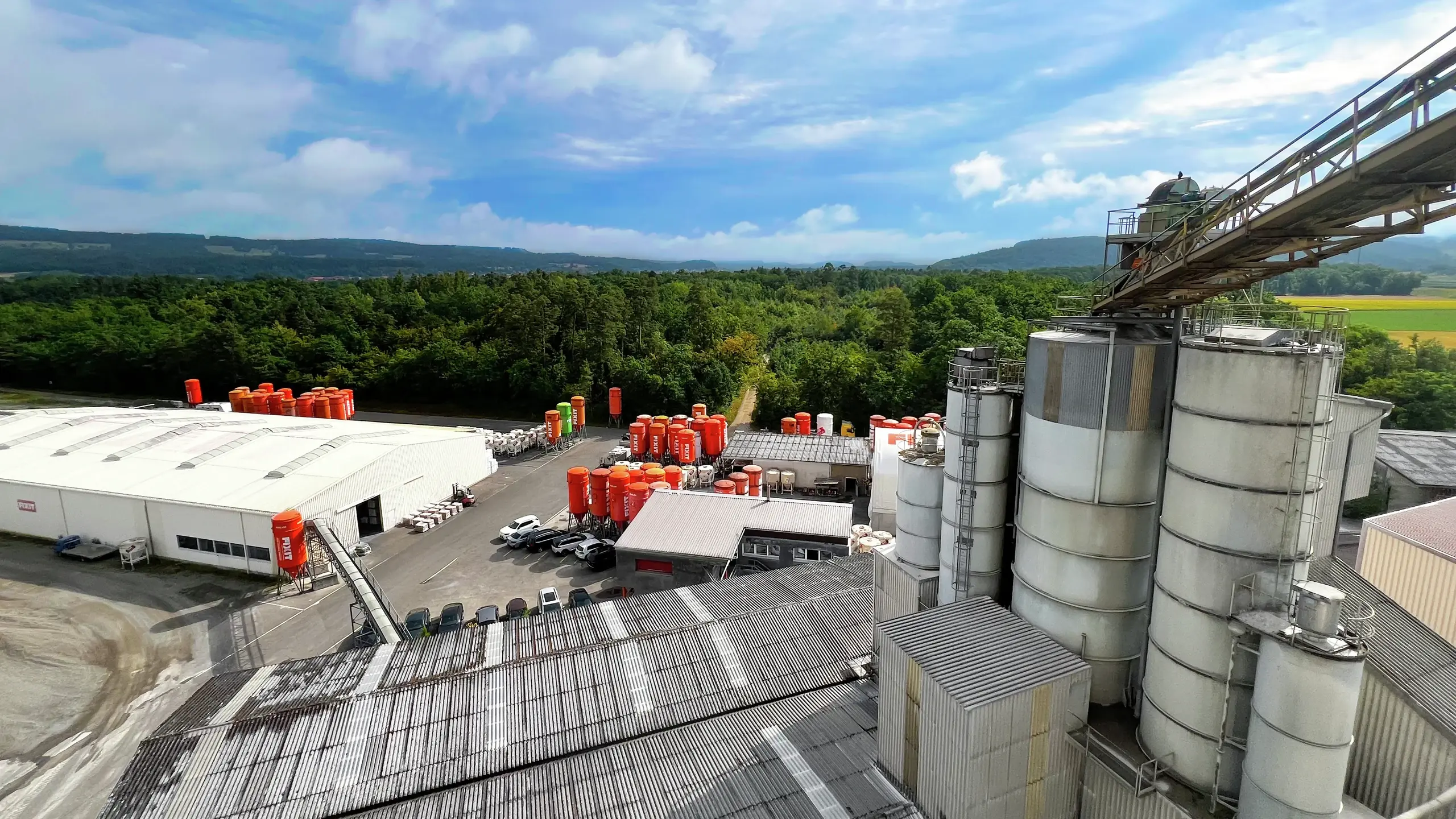 Produktionswerk mit Steinförderband, orangenen Fixit Silos und Hallen