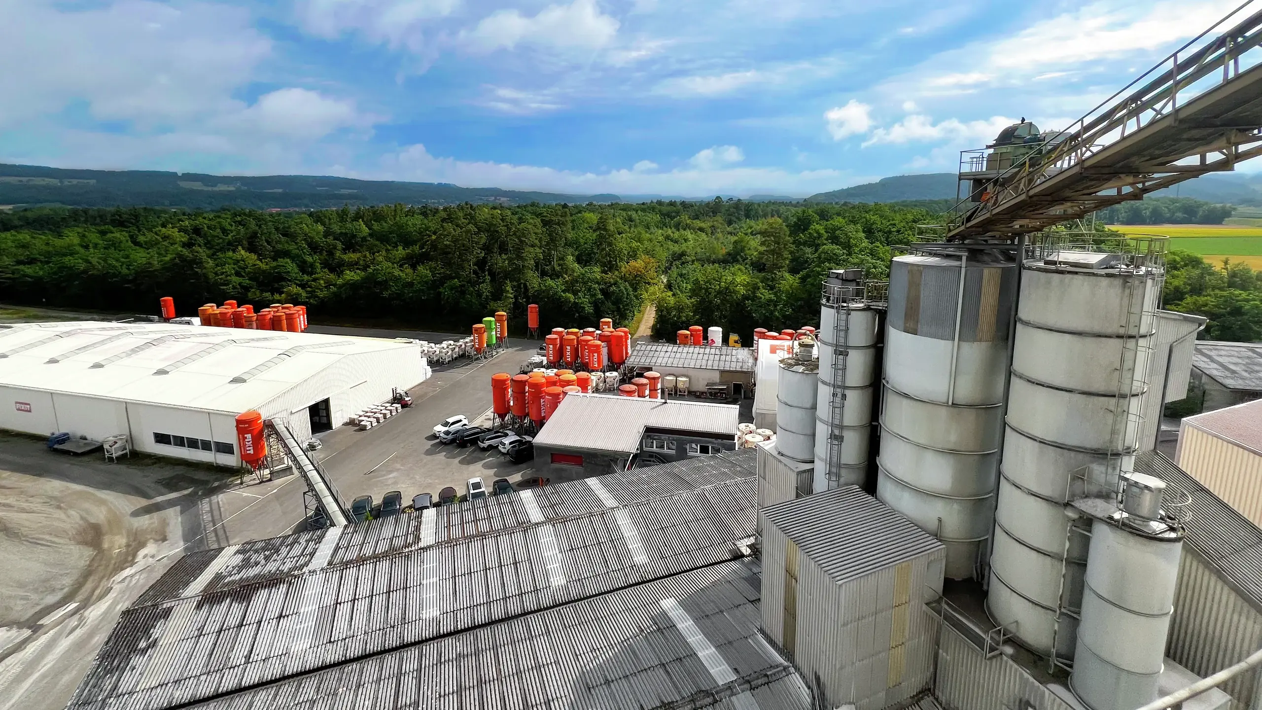 Usine de production équipée d'un convoyeur à pierres, de silos Fixit orange et de hangars
