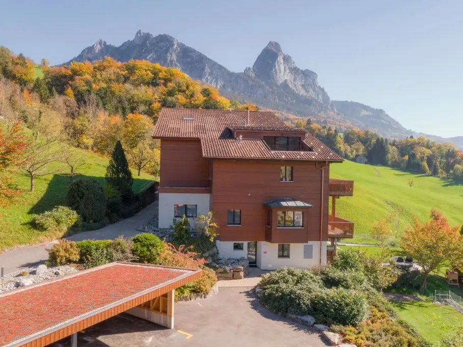 Seitenansicht des zweiteiligen Gebäudeesembles mit Bergpanorama im Hintergrund