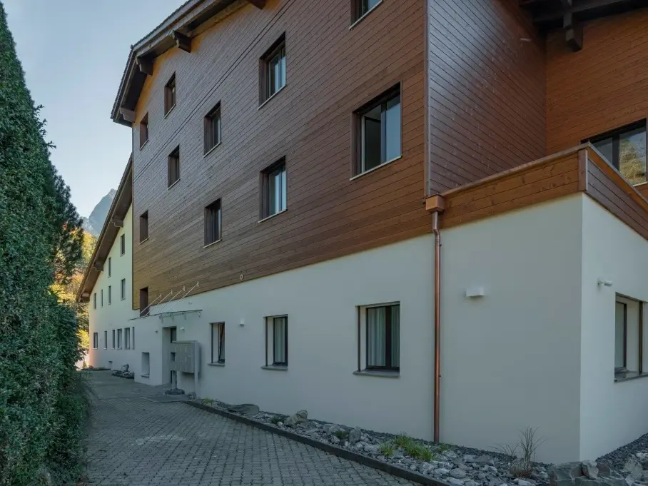 Detailansicht der Fassade, im ersten Stock weiss verputzt und darüber mit Holz verkleidet