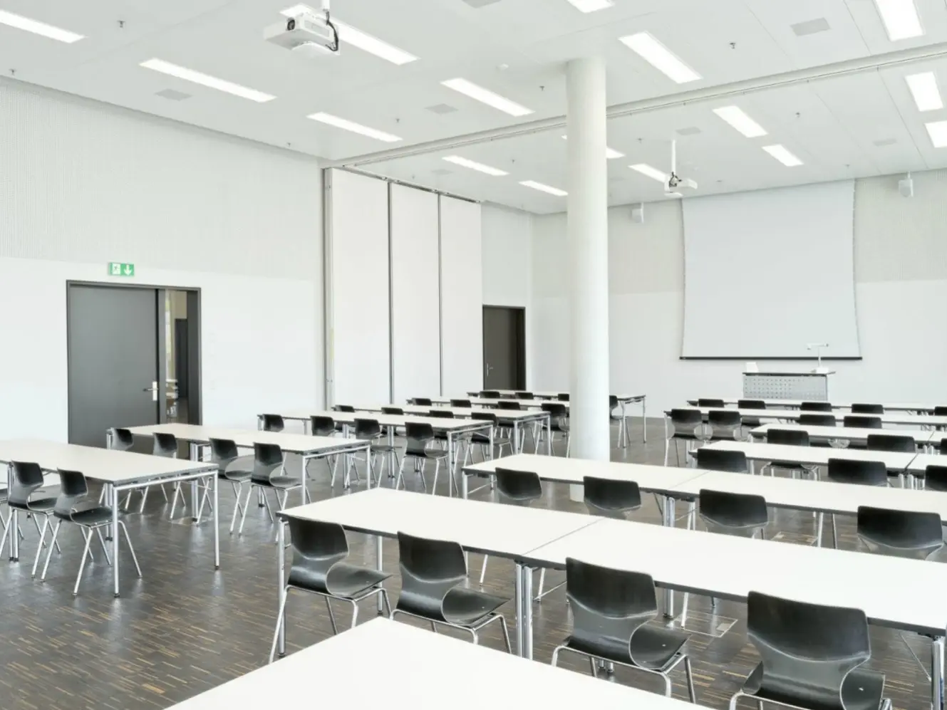 Weiss verputzter Innenraum mit Bestuhlung für einen Kurs, Whiteboard am Kopfende