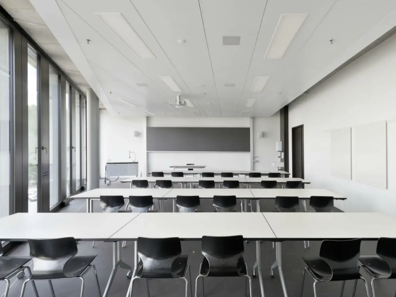 Weiss verputzter Innenraum aus Schülersicht, vorne ist eine Tafel angebracht