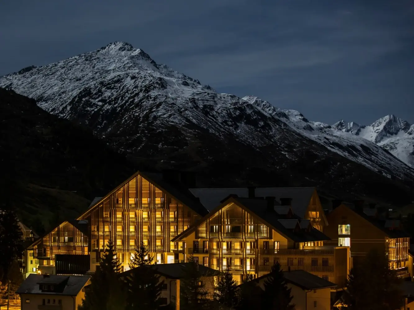 Photo de nuit de l'hôtel The Chedi à Andermatt avec panorama sur les montagnes