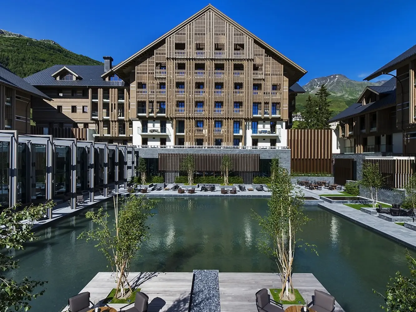 L'hôtel The Chedi, avec sa façade en bois et le plan d'eau devant le bâtiment