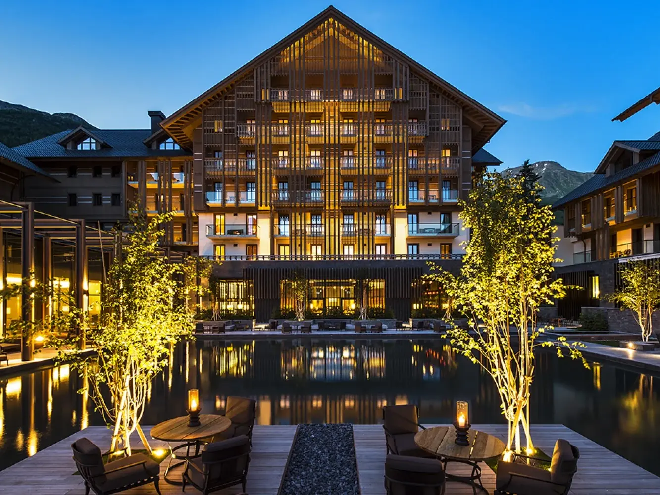  L'hôtel The Chedi, illuminé le soir, avec vue sur le plan d'eau en direction du bâtiment principal