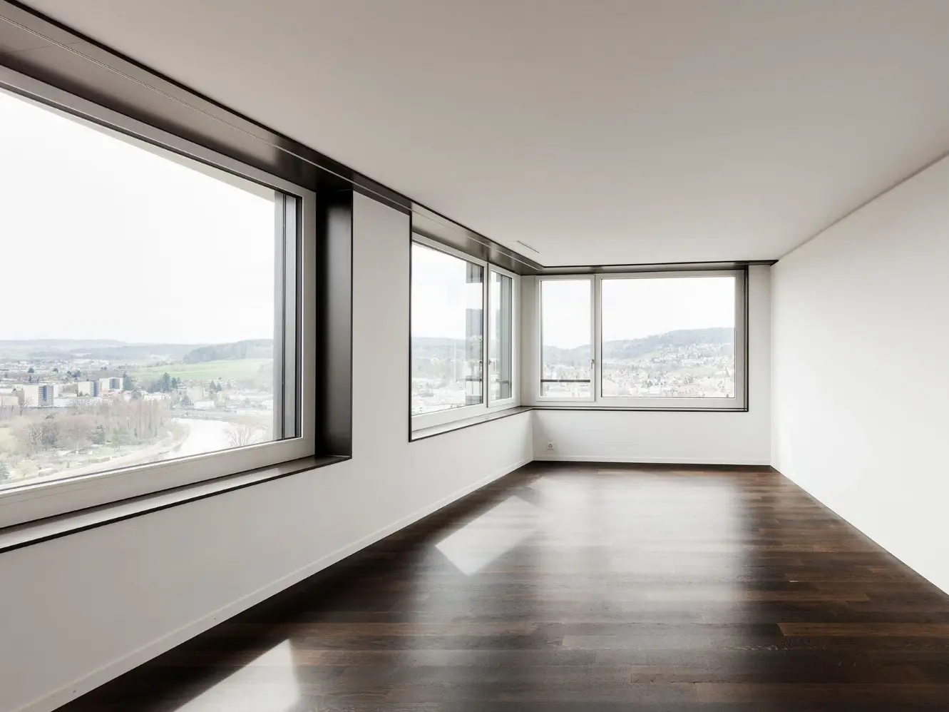 Innenraum mit dunklem Holzboden und grossen Fensterflächen