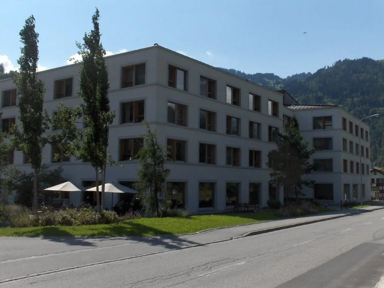 Bâtiment vu depuis la rue, avec deux arbres élancés