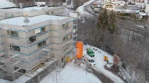Image prise par drone d'un immeuble collectif en gros œuvre, avec échafaudage et silo Fixit orange contenant du POR dans la neige