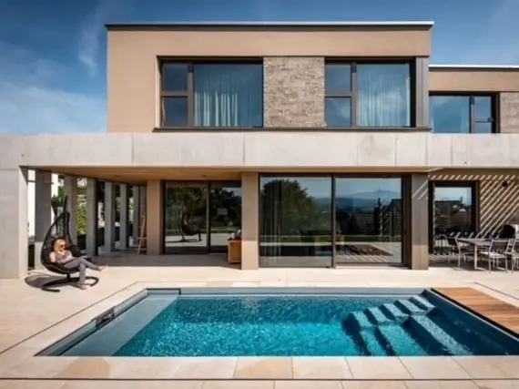 Türkiser Natursteinpool mit dem Gebäude im Hintergrund