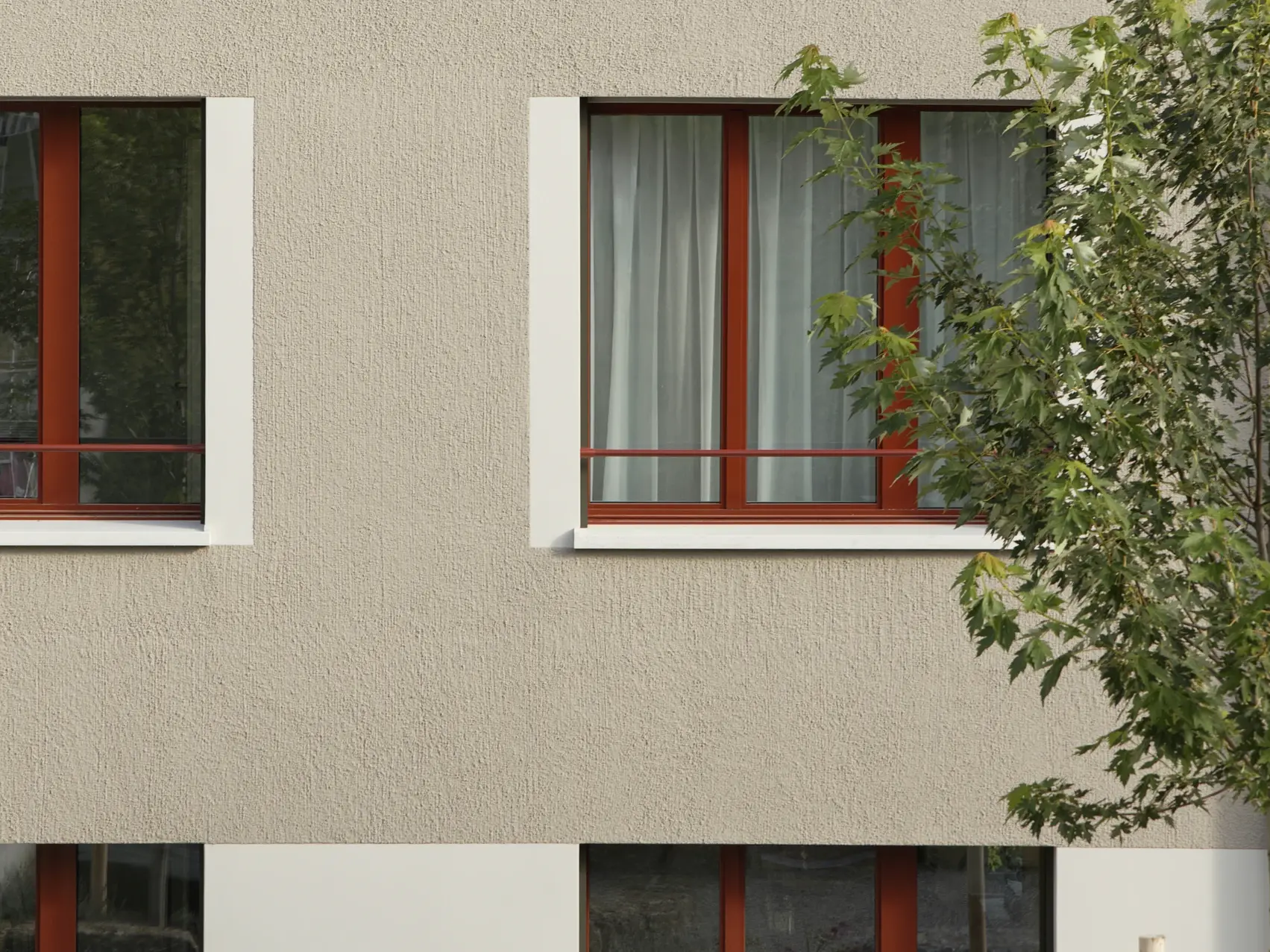 Vue détaillée de la façade avec son crépi beige, son premier étage clair et ses fenêtres encadrées