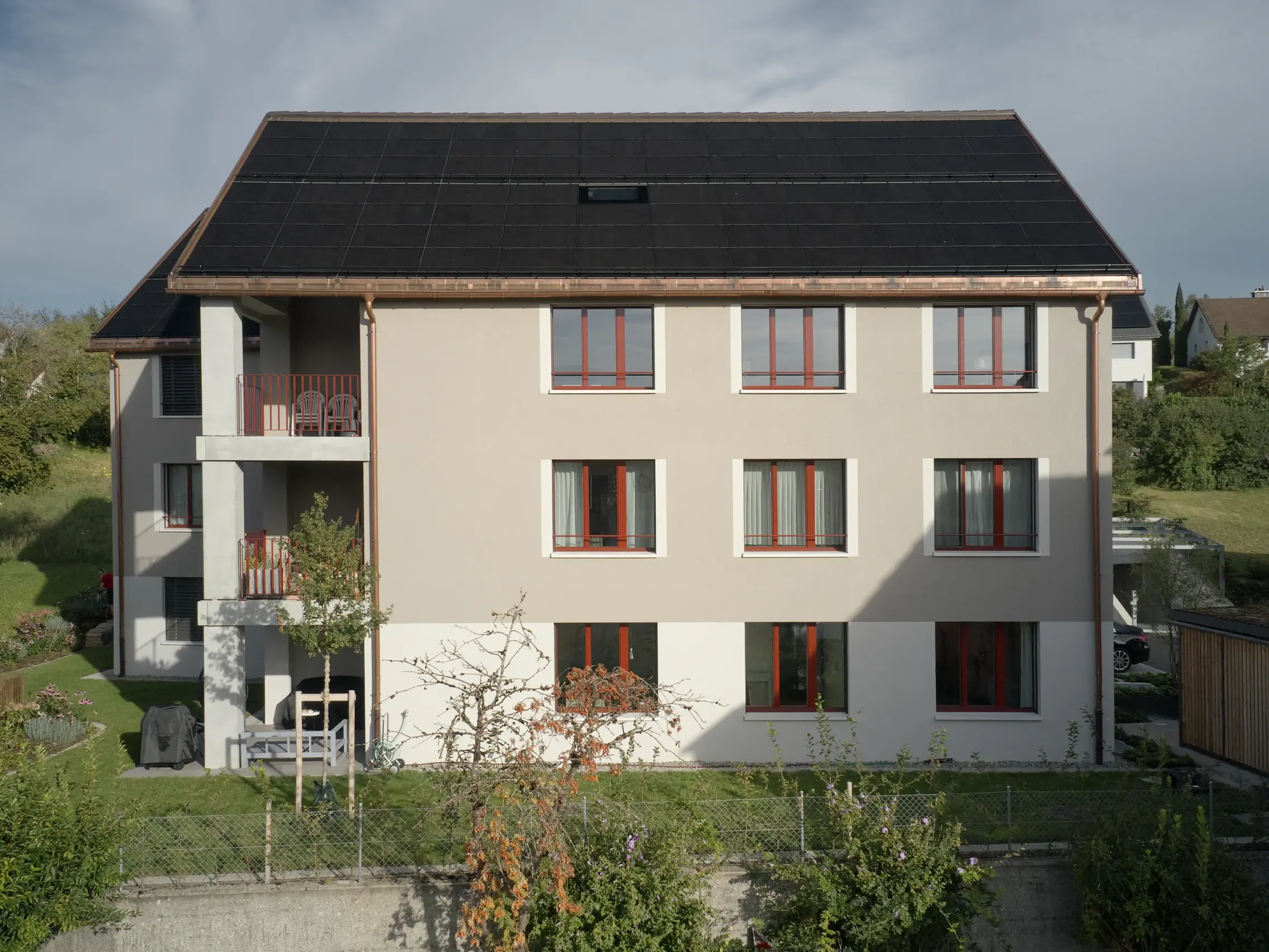 Vue d'ensemble de l'arrière du bâtiment avec l'installation photovoltaïque et le jardin