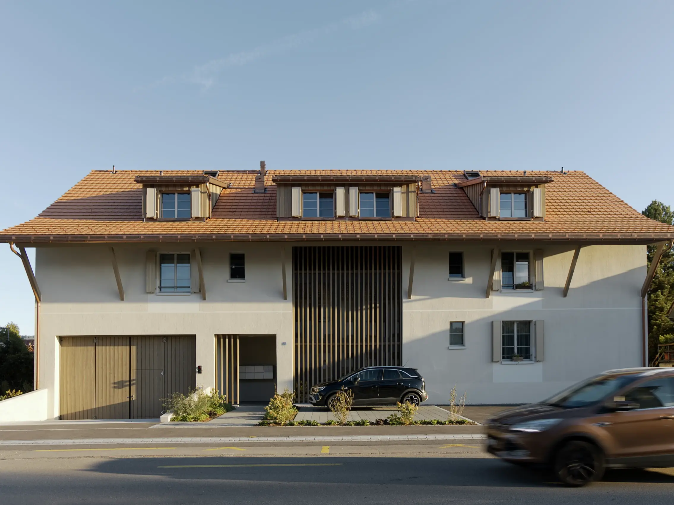 Vorderseite des Gebäudes von der Strasse, ein fahrendes Auto