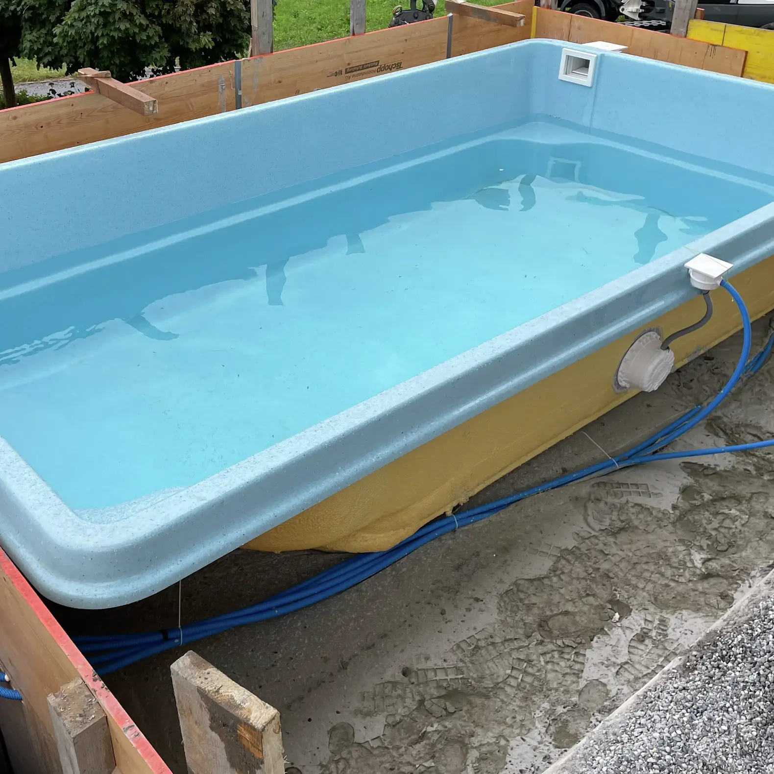 Cuve de piscine en PRV à prix abordable, avec intérieur bleu clair et extérieur jaune, à installer dans une fosse creusée dans le sol
