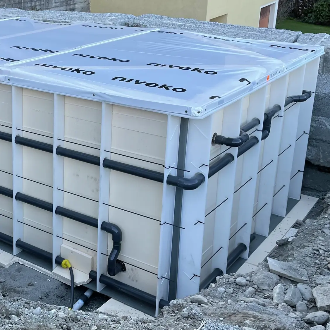  Cuve de piscine en PRV haut de gamme, dotée de renforts latéraux à l'extérieur pour assurer la stabilité et la fixation des canalisations ; la piscine est recouverte d'une bâche