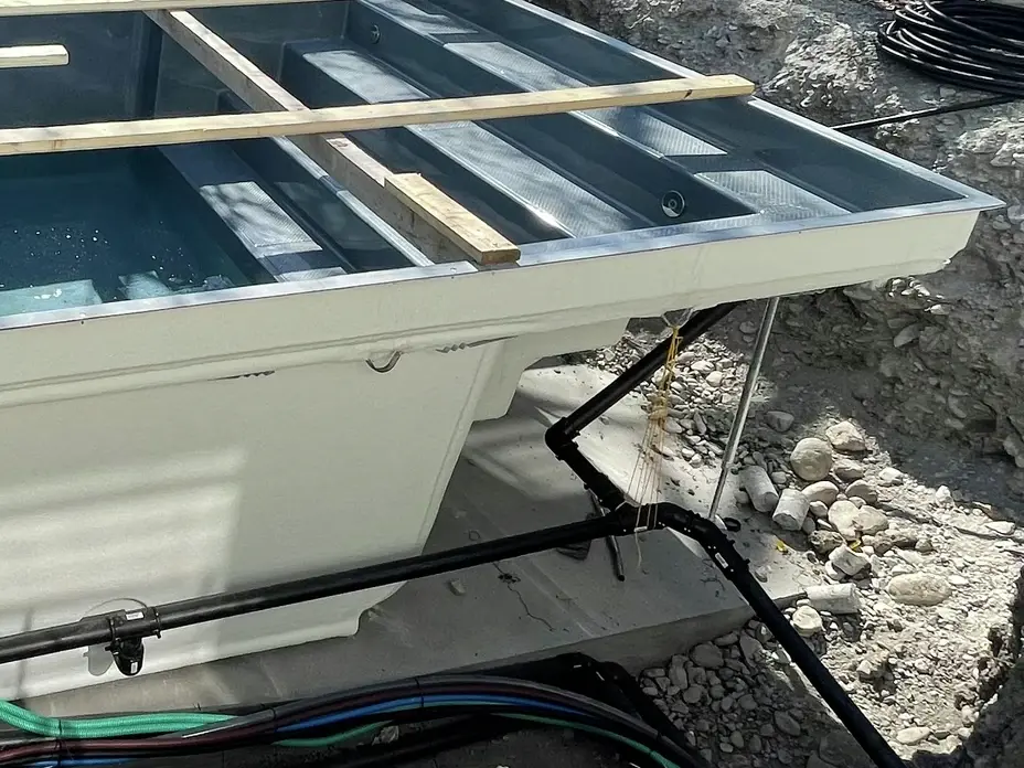  Coffrage de piscine avec une structure en escalier et un renfort métallique supplémentaire pour contrer la poussée hydrostatique, ainsi que des canalisations noires