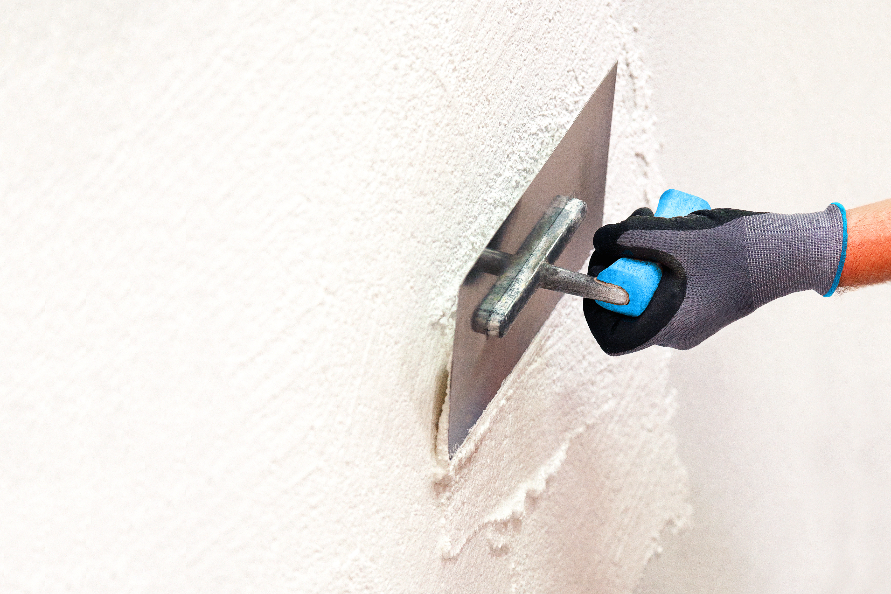 Hand mit Kelle verputzt eine Wand 