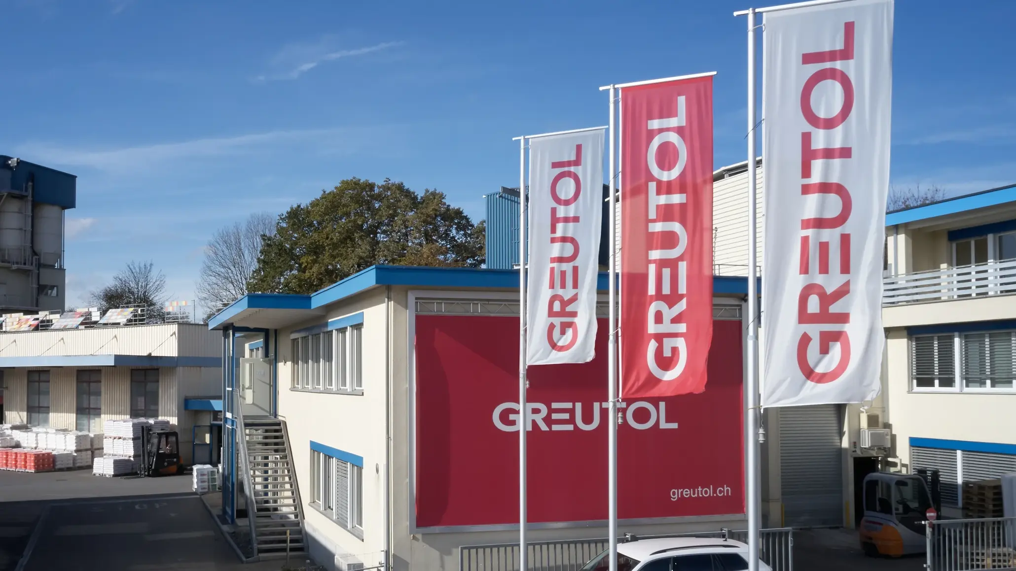 Greutol Gebäude in Otelfingen mit grosser Logo Wand und drei Greutol Fahnen