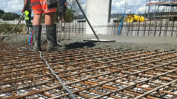 Des grilles d'armature en acier sur une fondation extérieure sont remplies de béton projeté.