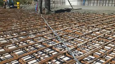 Des grilles d'armature en acier sur une fondation extérieure sont remplies de béton projeté.