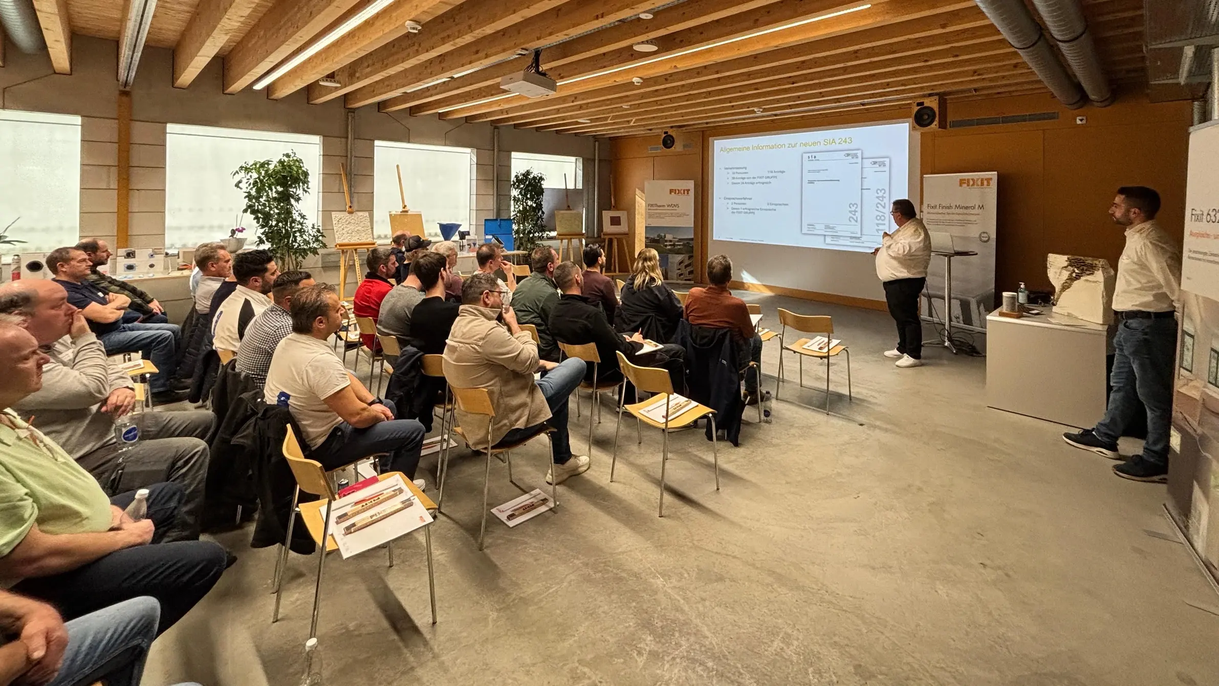 Raumansicht der Teilnehmenden am Fixit-Impuls-Flash auf linken Seite und Werner Wälle und die Präsentation auf der rechten Seite
