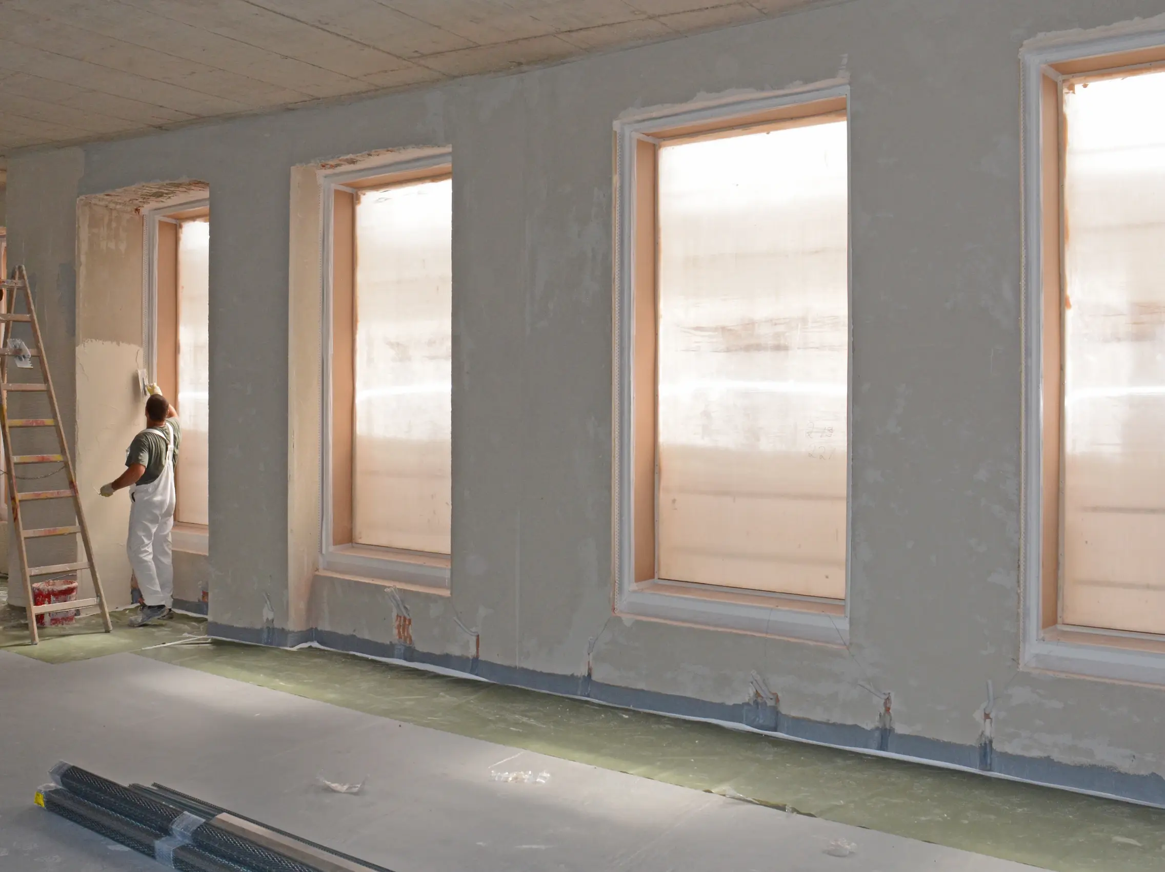 Dämmputz wird maschinell auf eine Innenwand aufgetragen und gleichmäßig verteilt.