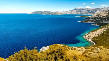 Région côtière en Croatie avec une mer bleue et des versants de montagne boisés, KI généré
