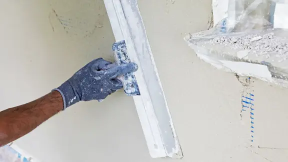 Hand verspachtelt eine Wand