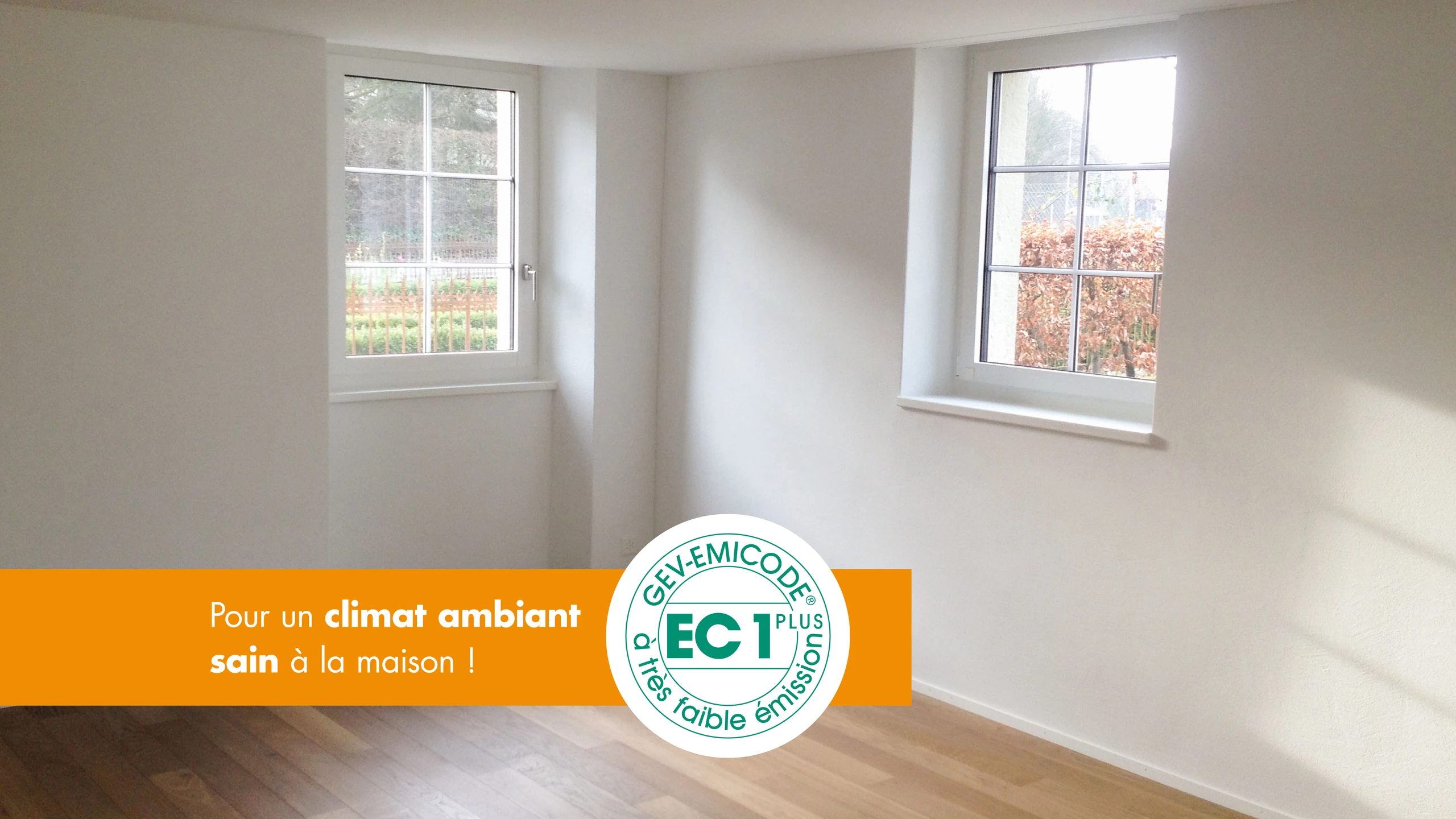 Intérieur avec deux fenêtres et un plancher en bois, overlay avec l'icône EMICODE® et le texte « Pour un climat intérieur sain à la maison !