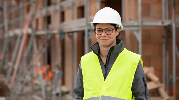 Bauleiterin mit Helm und Weste auf Baustellengelände