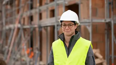 Bauleiterin mit Helm und Weste auf Baustellengelände