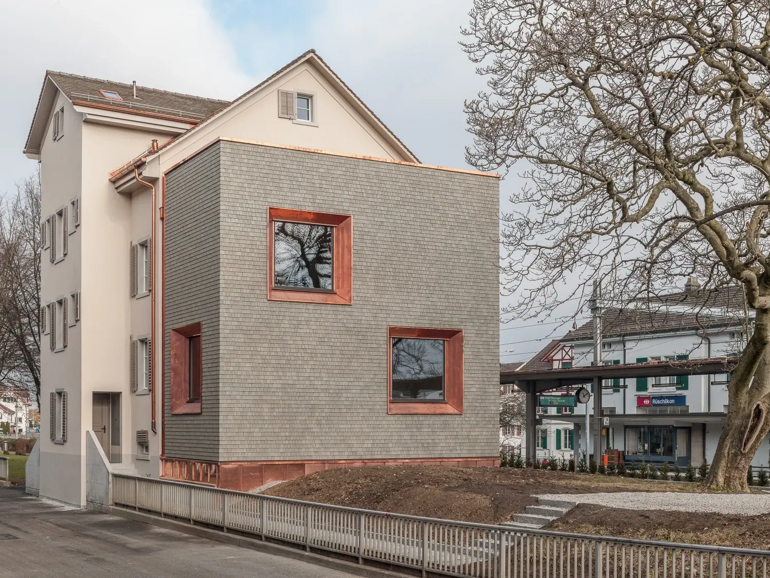 Das sanierte Haus mit hellem Putz und einem kubischen Anbau mit grauer Holzvertäfelung
