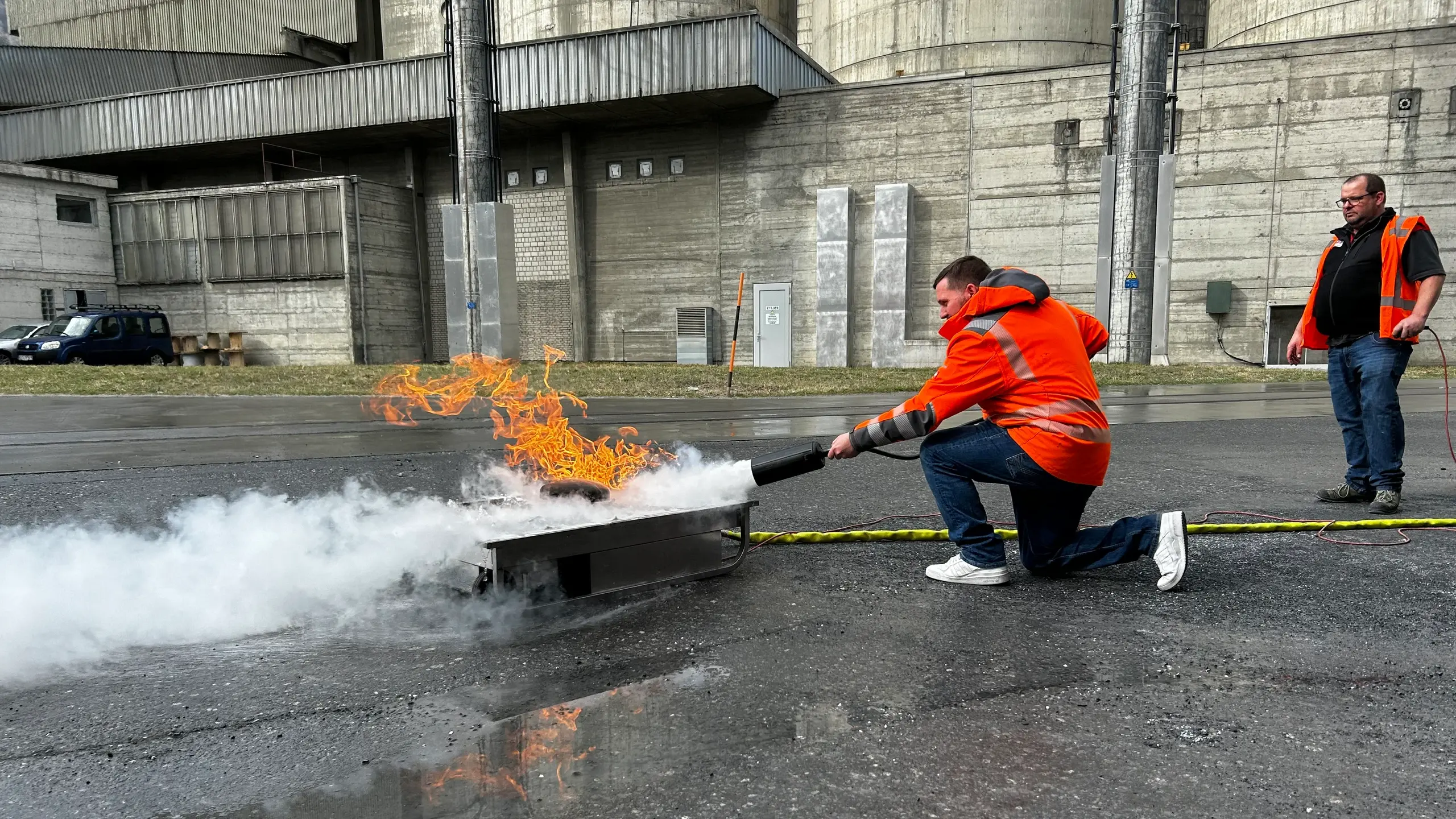 Ein Mitarbeiter löscht den Testbrand mit einem Feuerlöscher unter Aufsicht des Lehrers