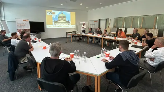 Salle de séminaire avec les participants de HUG Baustoff AG et un message de bienvenue