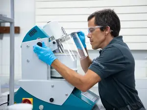 Un employé de laboratoire teste un matériau à l'aide d'un agitateur en tenue de protection