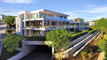 Immeuble moderne avec de grands balcons avec une façade extérieure individuelle : crépi combiné avec une maçonnerie apparente en pierre naturelle