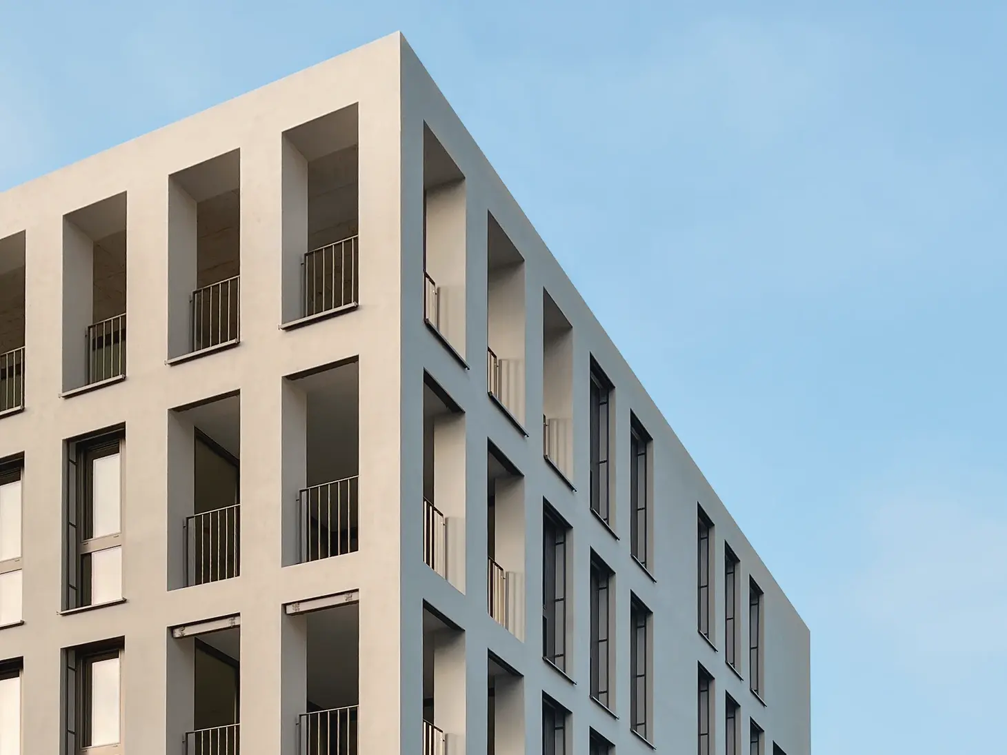 Modernes Flachdachgebäude mit hochwertiger Fassadengestaltung, bei dem der Dachrand gestalterisch zurückgenommen und dezent ausgeführt ist.