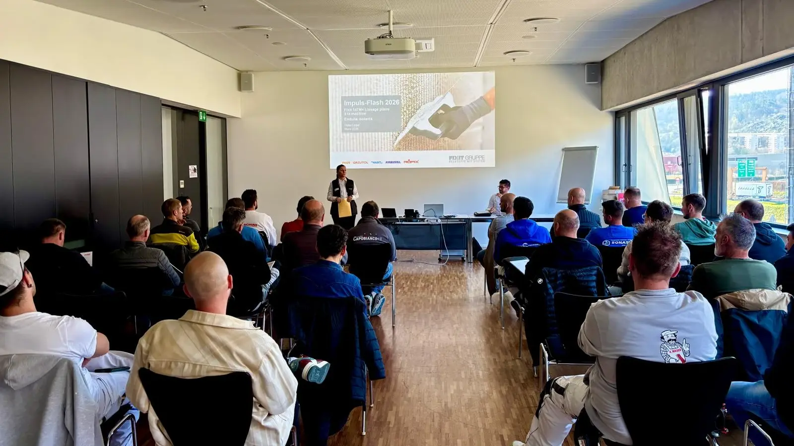 Teilnehmende sitzen vor der Präsentation und Rana Mehaidli begrüsst die französischsprachigen Teilnehmenden