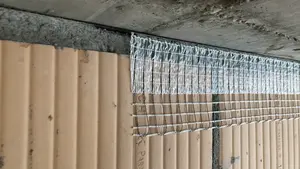 Transition de matériau d'une dalle en béton à une maçonnerie en briques et bande de découplage Stucanet® Easy Fix déjà collée