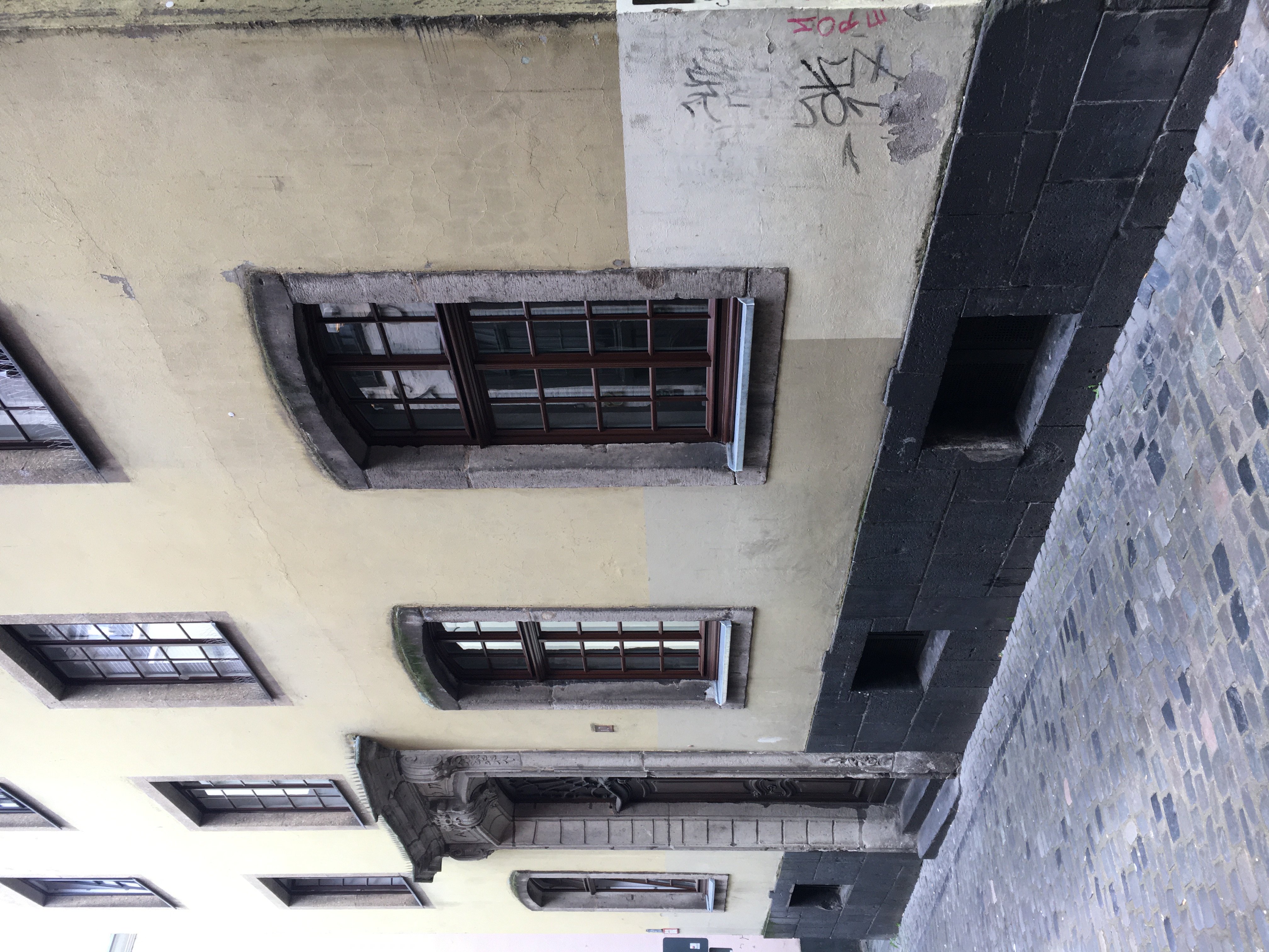 Vor der Sanierung: Die alte Fassade war mit den unterschiedlichen Putzmaterialien, Rissen, Abplatzungen und Moosbewuchs auf 