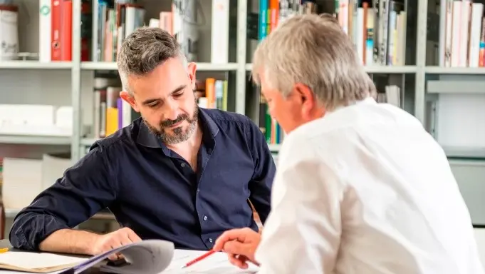 Zwei Personen im angeregten Gespräch mit Bücherregal im Hintergrund