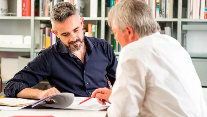 Deux personnes en pleine conversation animée, avec une bibliothèque en arrière-plan