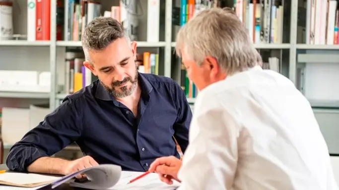 Two people engaged in lively conversation with a bookshelf in the background
