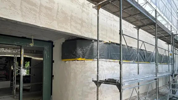 Detailansicht des Eingangsbereichs mit einer geschwungenen Fassadenfläche nach der Verarbeitung des Fixit 462 Renovationsputzes