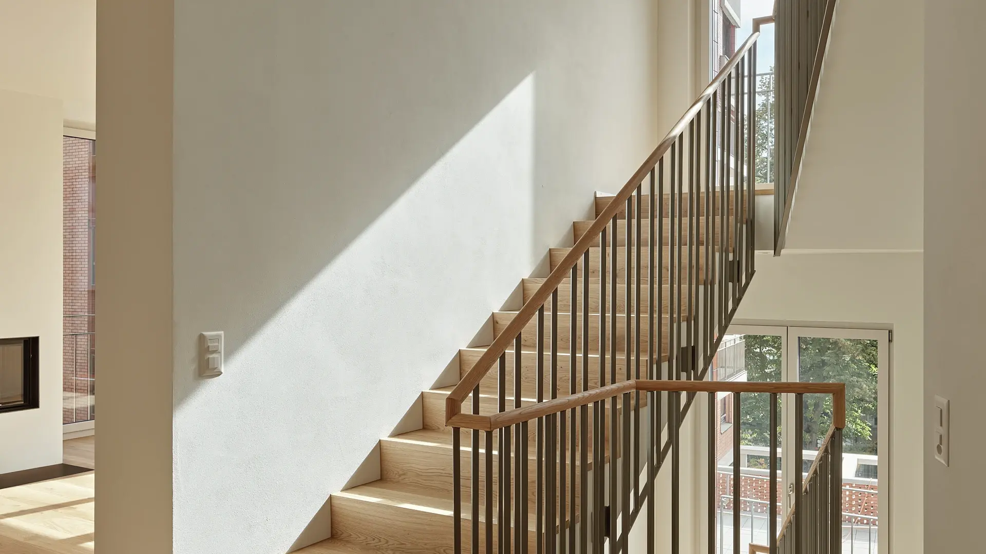 Cage d'escalier moderne avec un crépi blanc et la lumière du soleil qui pénètre par une fenêtre