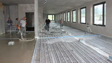 Chantier à l'intérieur avec les registres de chauffage posés pour le chauffage au sol. Sur le côté gauche, la chape fluide a déjà été coulée.