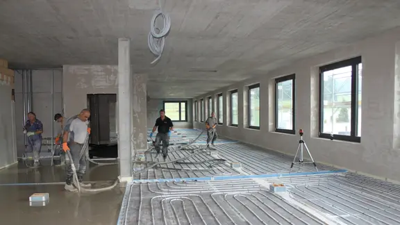 Chantier à l'intérieur avec les registres de chauffage posés pour le chauffage au sol. Sur le côté gauche, la chape fluide a déjà été coulée.