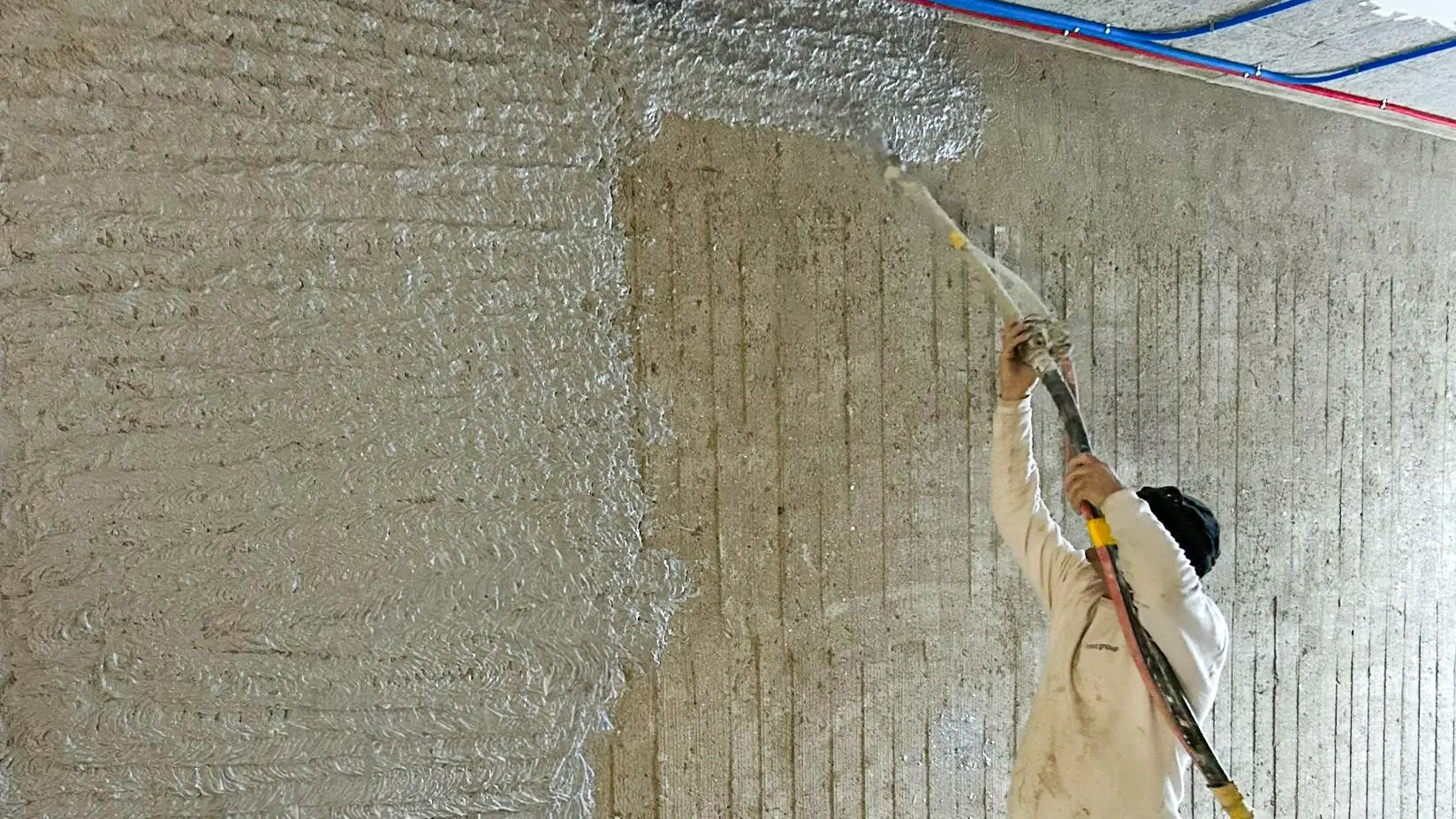 Verarbeiter bringt Fixit 125 M im Spritzauftrag auf eine nicht vorbehandelte Wand auf