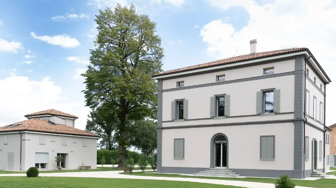 Due edifici in stile mediterraneo con facciata esterna recentemente ristrutturata, di colore bianco con elementi grigi a contrasto